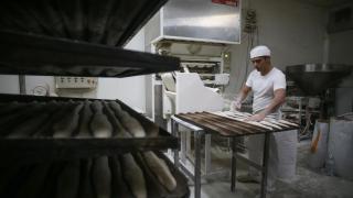 Un trabajador en un obrador preparando barras de pan.