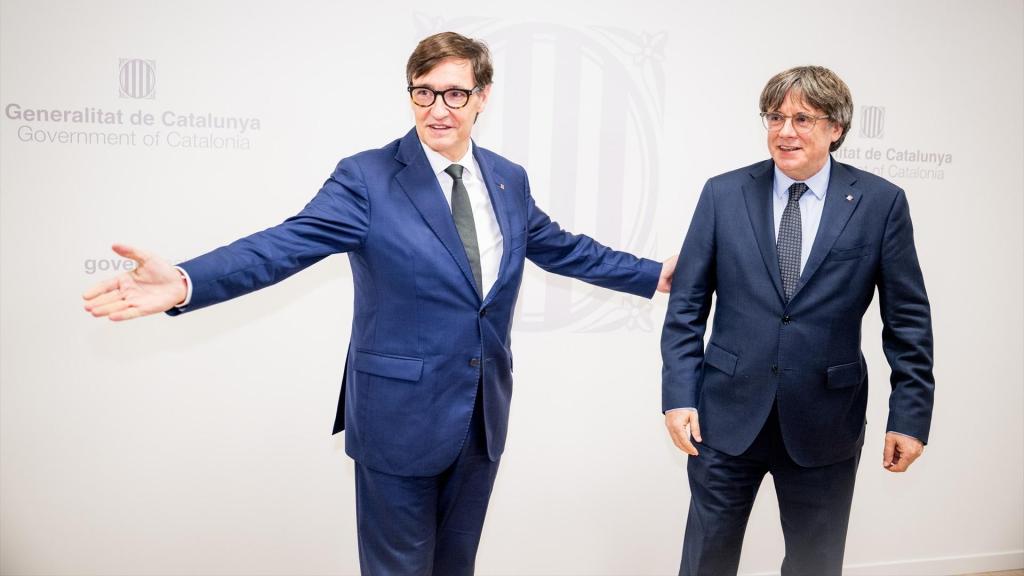 El presidente de la Generalitat, Salvador Illa (i), saluda al líder de Junts per Catalunya, Carles Puigdemont (d).