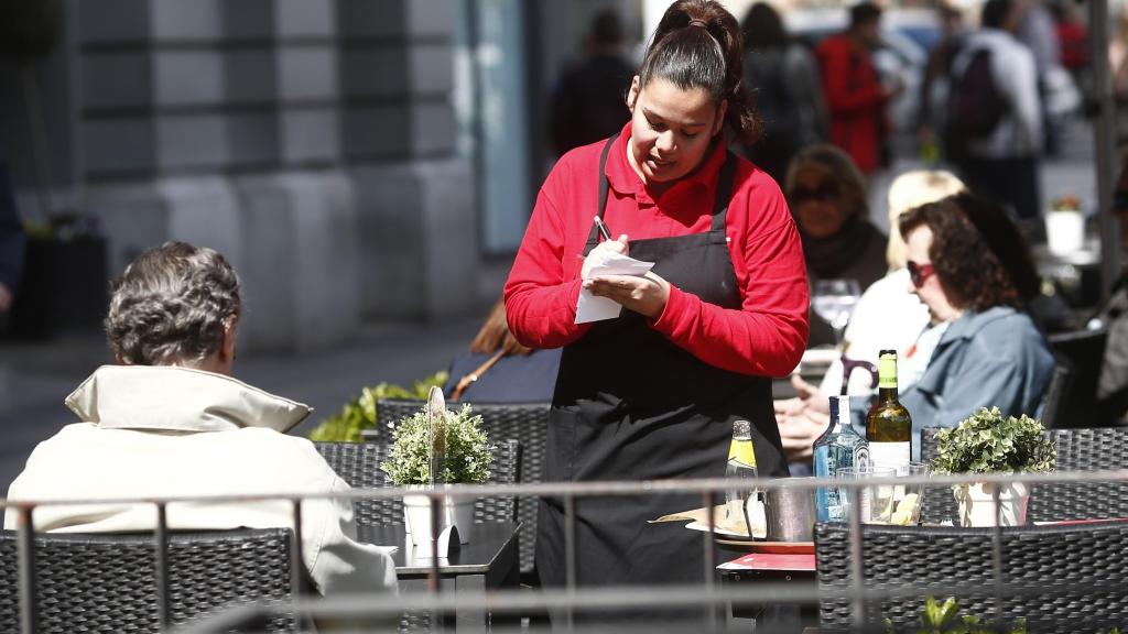 Imagen de archivo de una camarera atendiendo a unos clientes