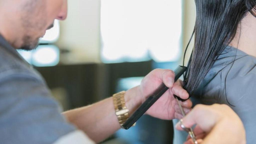 Peluquero cortando el pelo a su clienta.