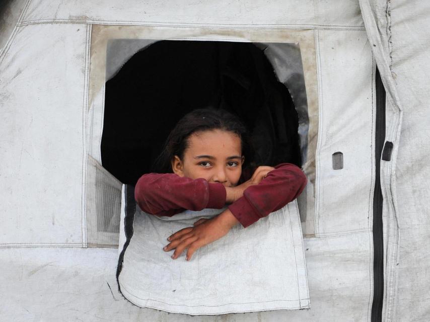 Una niña palestina desplazada mira desde la tienda de campaña de su familia en Gaza.
