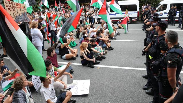 Agentes de la Ertzaintza vigilan a varios manifestantes propalestinos durante una etapa de La Vuelta.