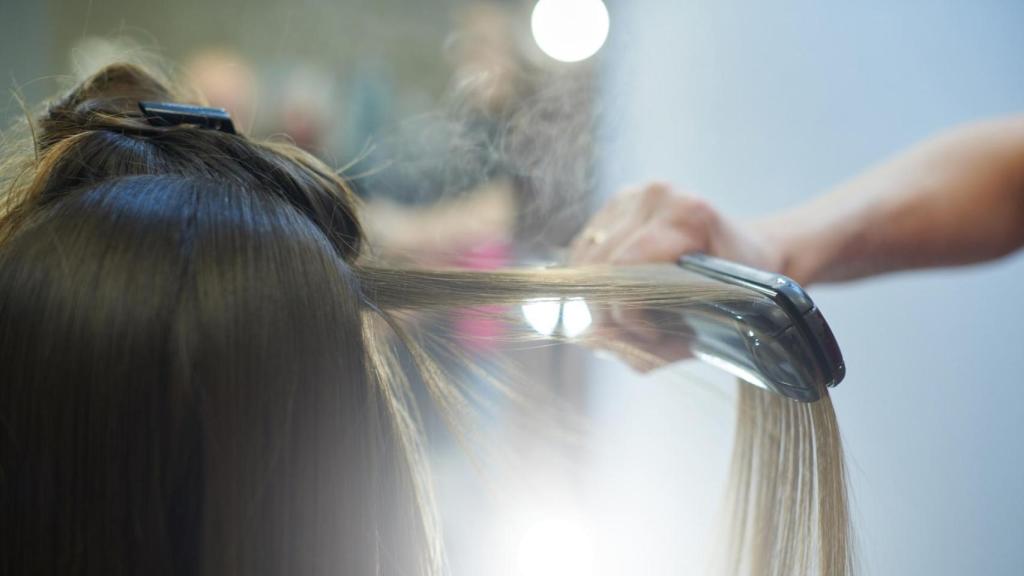 Una mujer planchándose el pelo