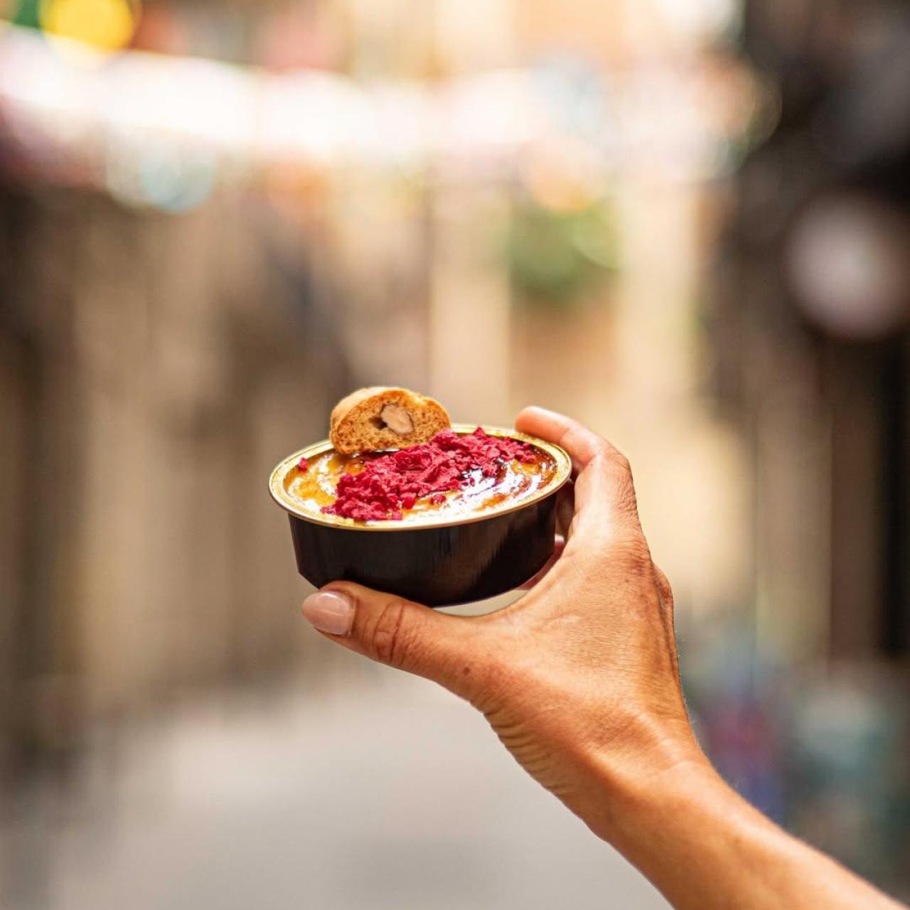 Una tarrina de crema catalana con frambuesa deshidratada.