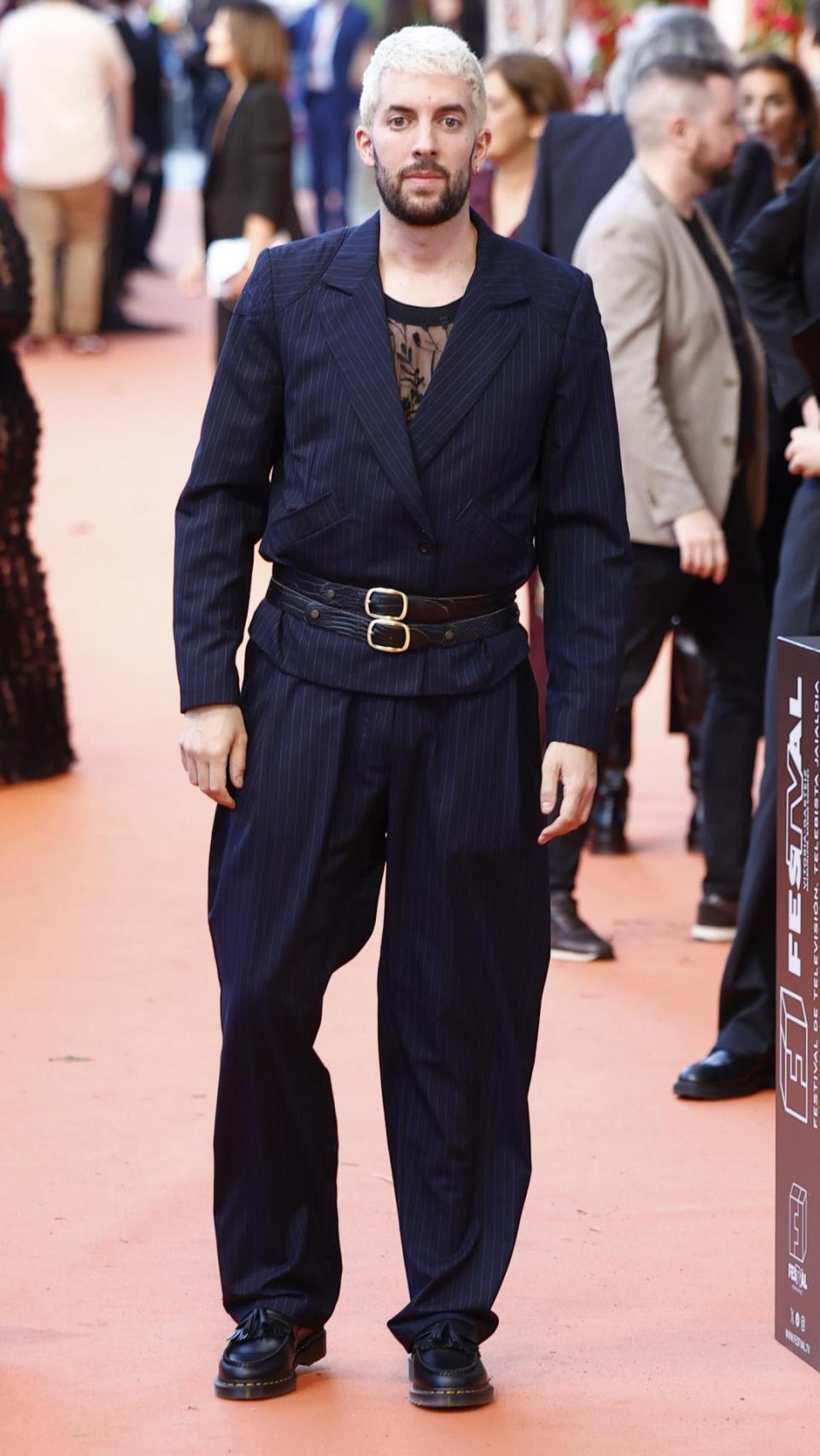 David Broncano luciendo un traje de raya diplomática, top de encaje y doble cinturón.