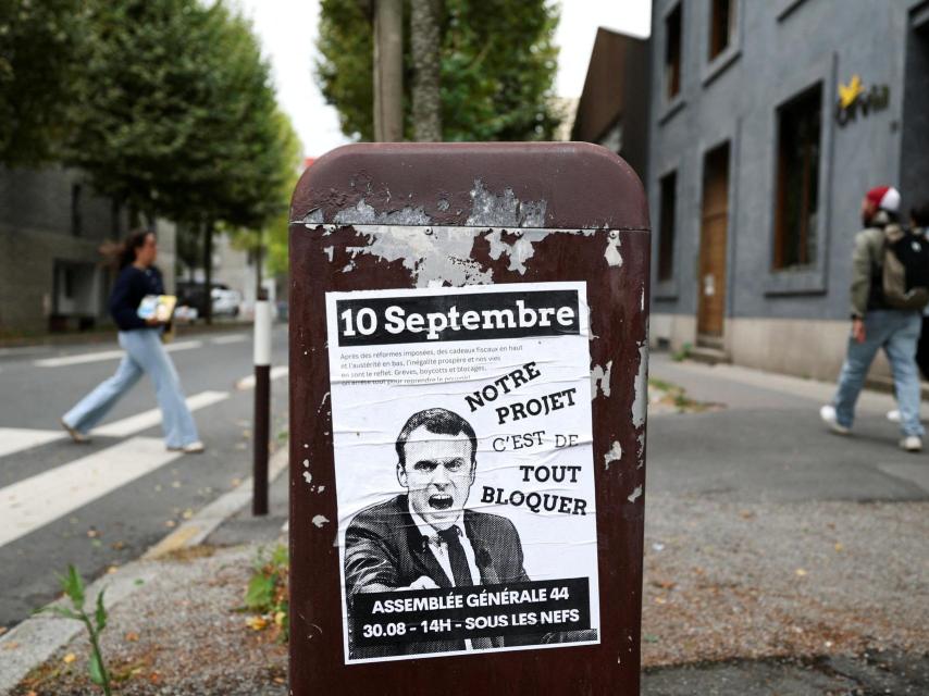 La gente pasa junto a un cartel que representa al presidente francés Emmanuel Macron con el lema Notre projet c'est de tout bloquer (Nuestro proyecto es bloquearlo todo).