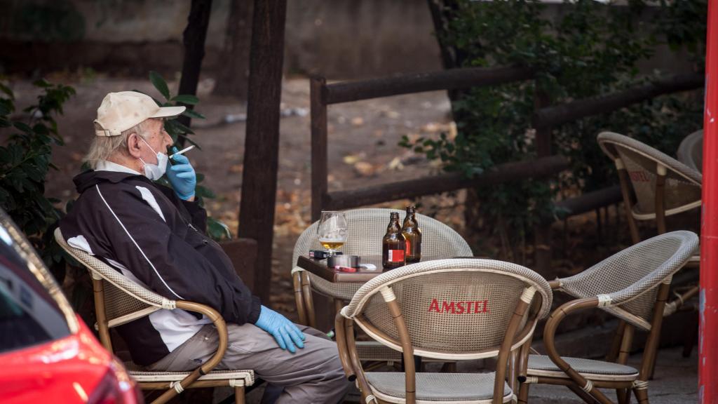 Un hombre fumando en una terraza de un bar durante la pandemia.