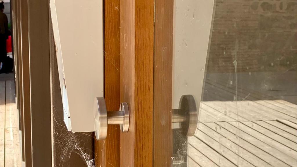 Fotografía difundida por el PSOE de Toledo con telarañas en la puerta de entrada del edificio.