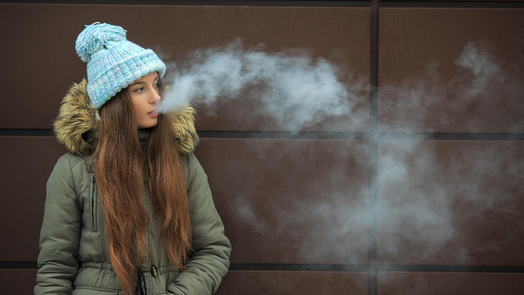 Una joven, consumiendo un vaper.
