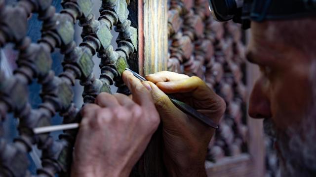 El restaurador Miguel Bonache limpia la celosía de madera que revela un intenso tono verde.