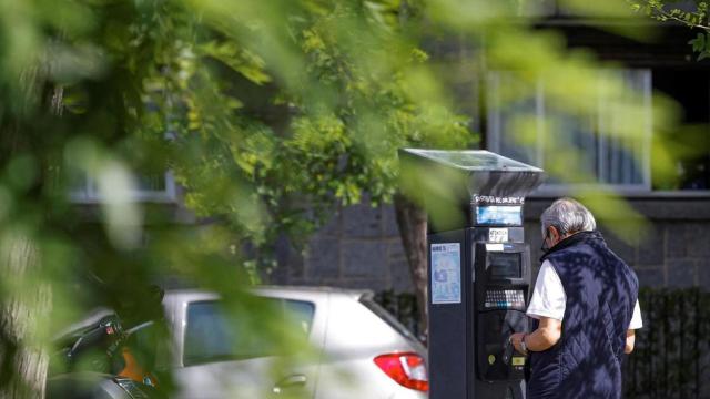 Un hombre pagando en un parquímetro.
