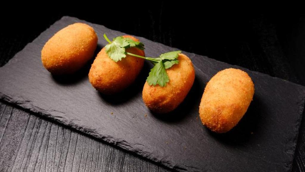 Croquetas de jamón sobre una pizarra.
