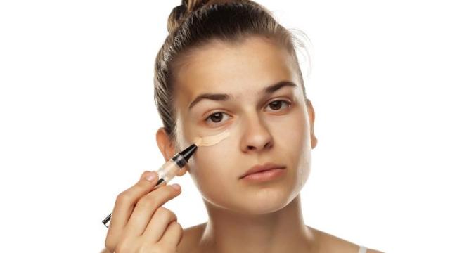 Joven aplicándose corrector de ojeras.