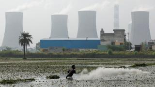 Un hombre pesca frente a una explotación de combustibles fósiles.