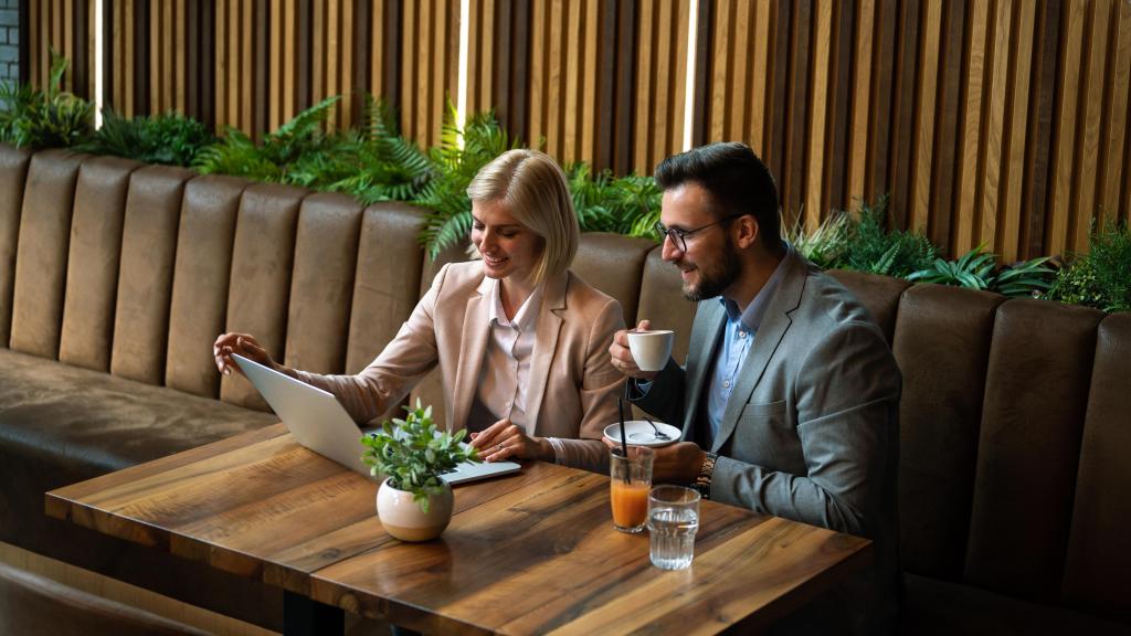 Imagen de archivo de dos compañeros de trabajo reunidos en una cafetería.
