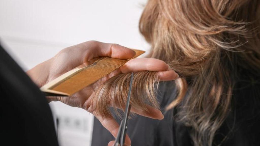 Mujer cortándose el pelo.