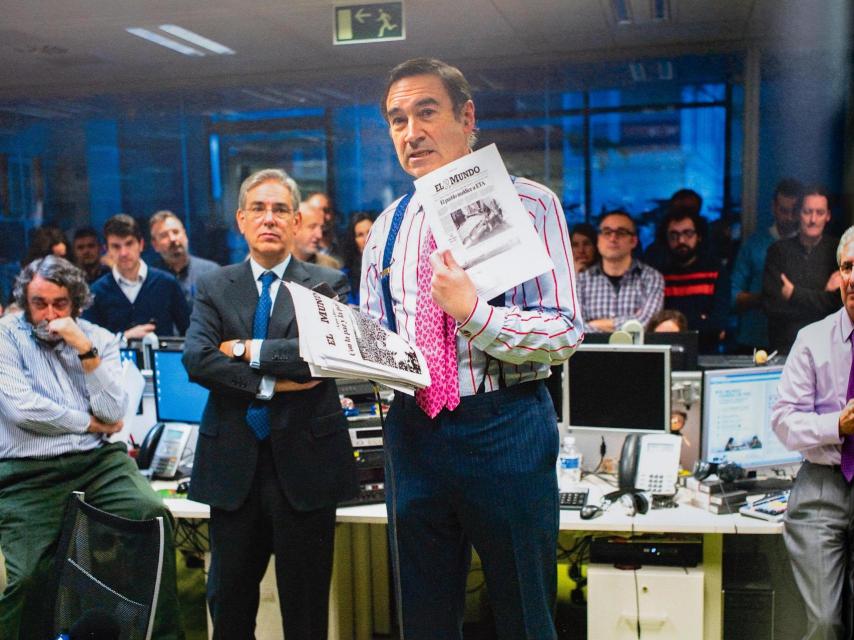 Pedro J. Ramírez, duante su discurso, mostrando algunas de las portadas más relevantes publicadas por El Mundo bajo su dirección. A la izquierda, Pedro García Cuartango y Antonio Fernández Galiano. En segundo plano, Vicente Ruiz, Juan Carlos Laviana, Fernando Baeta, Ferrán Boiza, Joaquín Manso y Rafa J. Álvarez.