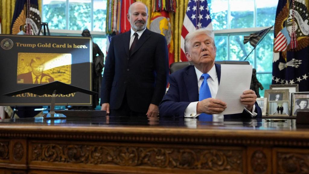 El presidente de Estados Unidos, Donald Trump , observa sentado junto a un cartel que dice  La tarjeta dorada de Trump está aquí, con el secretario de Comercio de Estados Unidos, Howard Lutnick, a su lado, en la Oficina Oval de la Casa Blanca en Washington, DC, Estados Unidos, el 19 de septiembre de 2025.