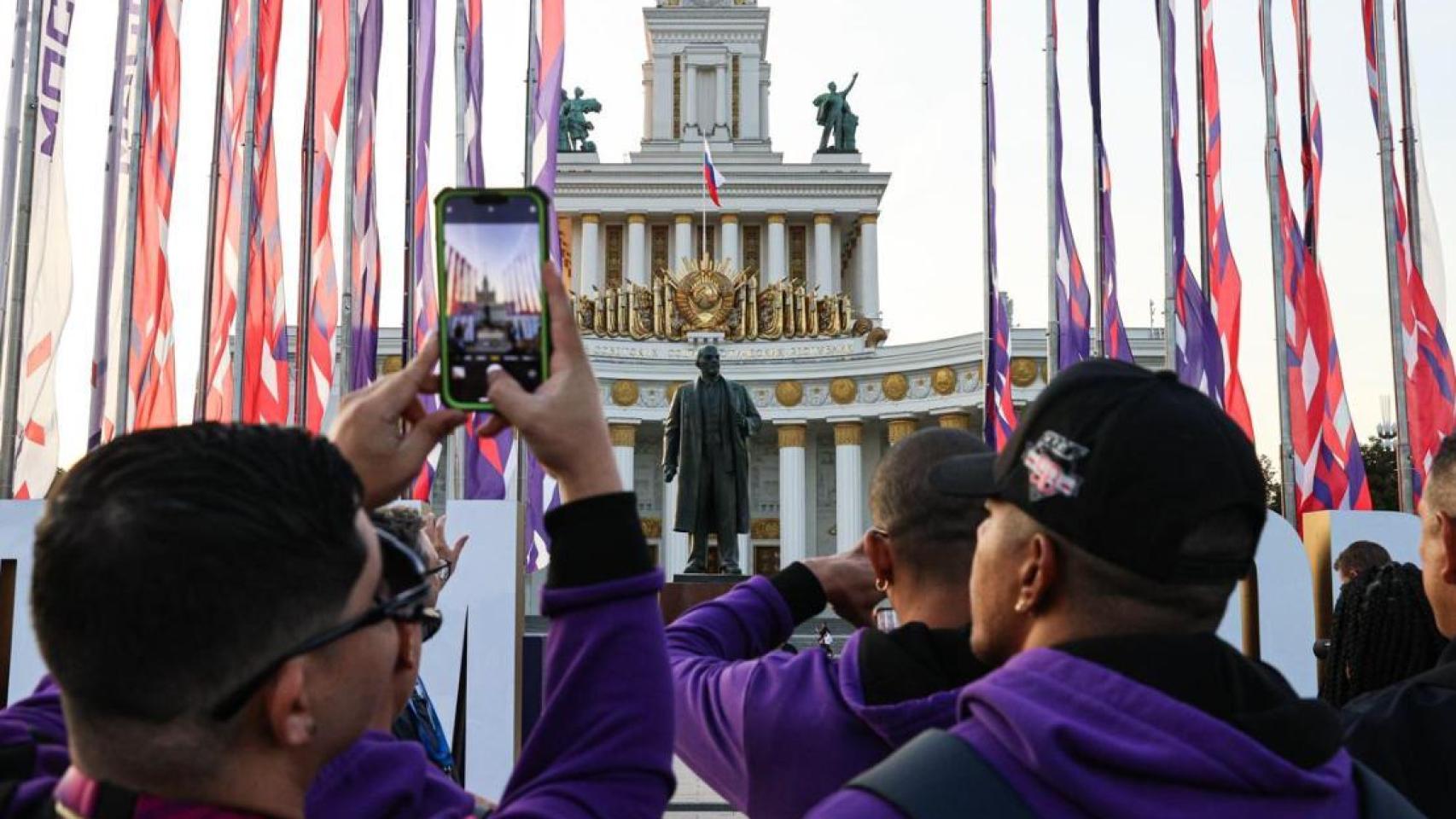 Cantantes de Kenia, Catar y Venezuela frente a una estatua de Lenin en Moscú.