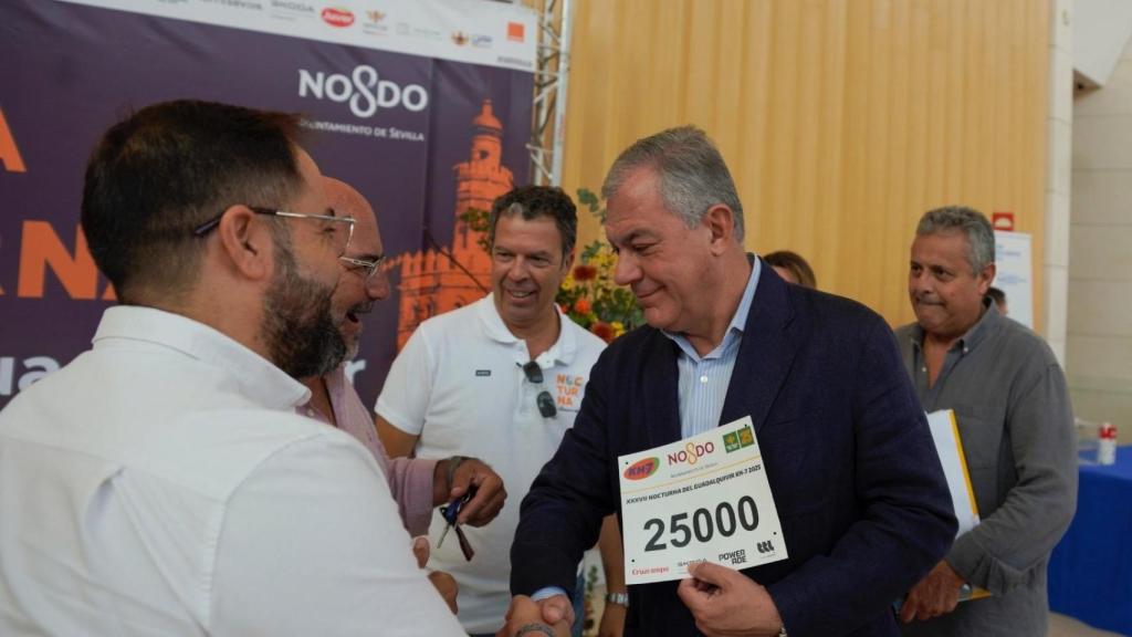 El alcalde de Sevilla, José Luis Sanz, entrega uno de los dorsales de la XXXVII carrera nocturna del Guadalquivir.