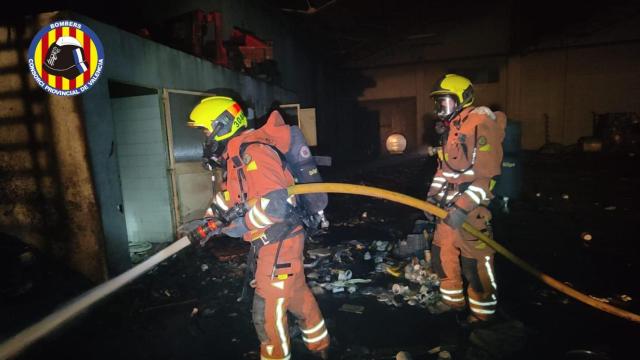 Bomberos en el interior de la fábrica incendiada de Silla.
