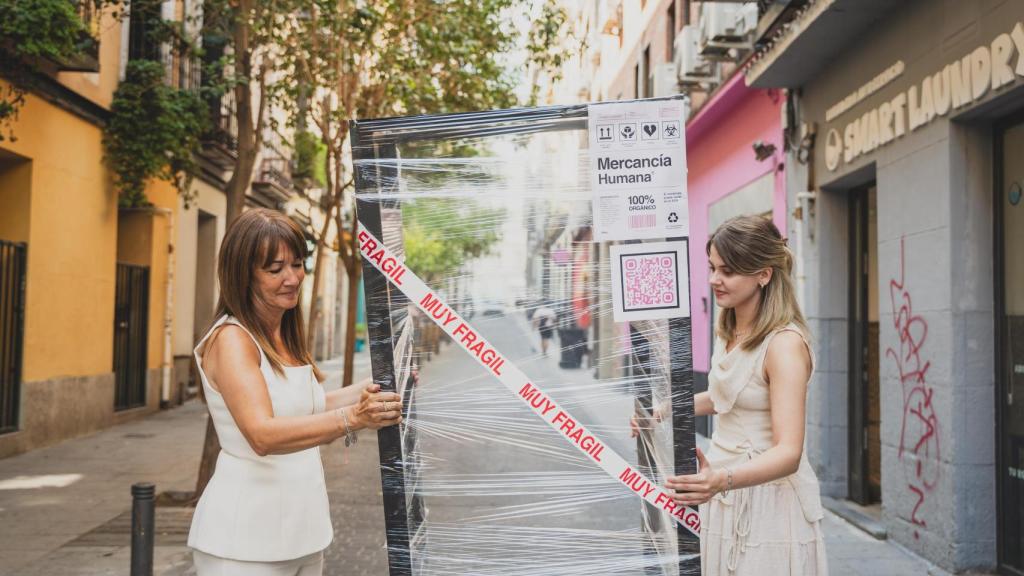 Rocío Mora y una redactora de EL ESPAÑOL, llevando juntas la caja por las calles de Madrid.
