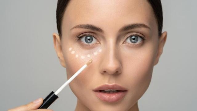 Mujer maquillándose con corrector.