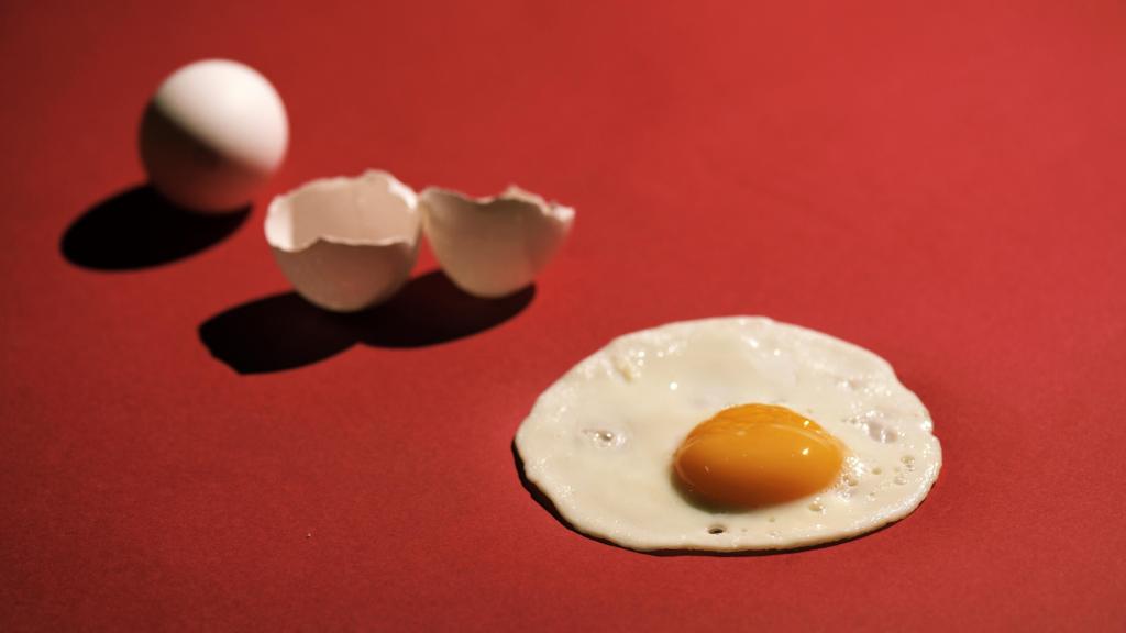 Un huevo frito sobre fondo rojo.