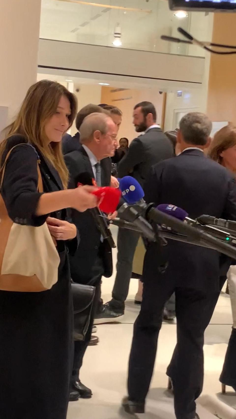 Carla Bruni atendiendo a la prensa y tapando el micrófono.