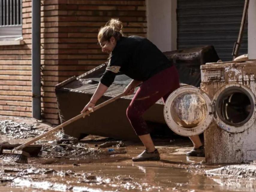 Una mujer limpia los estragos dejados por la dana en Utiel, Valencia.