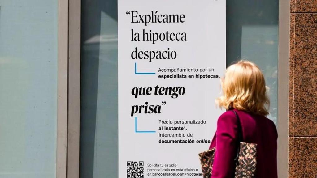 Una mujer ante un cartel bancario sobre las hipotecas.