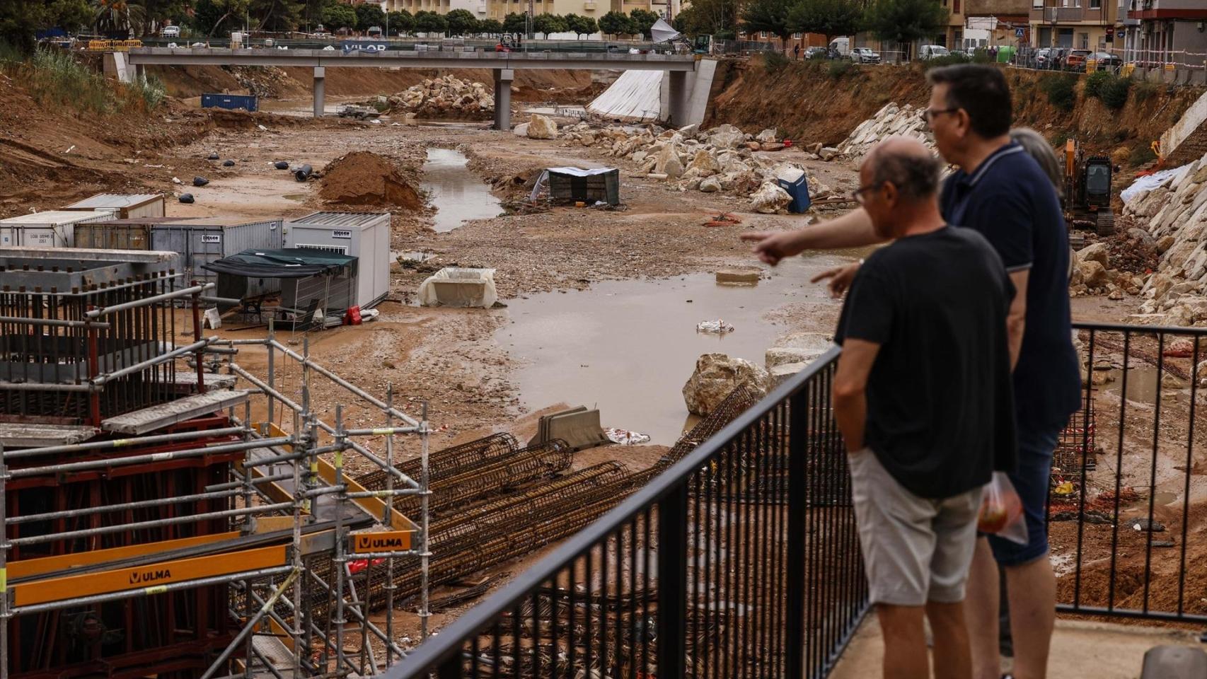 Dos hombres observan el barranco del Poyo a su paso por Paiporta tras las lluvias de este lunes. Rober Solsona / EP
