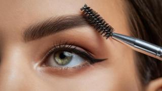 Mujer peinándose las cejas.