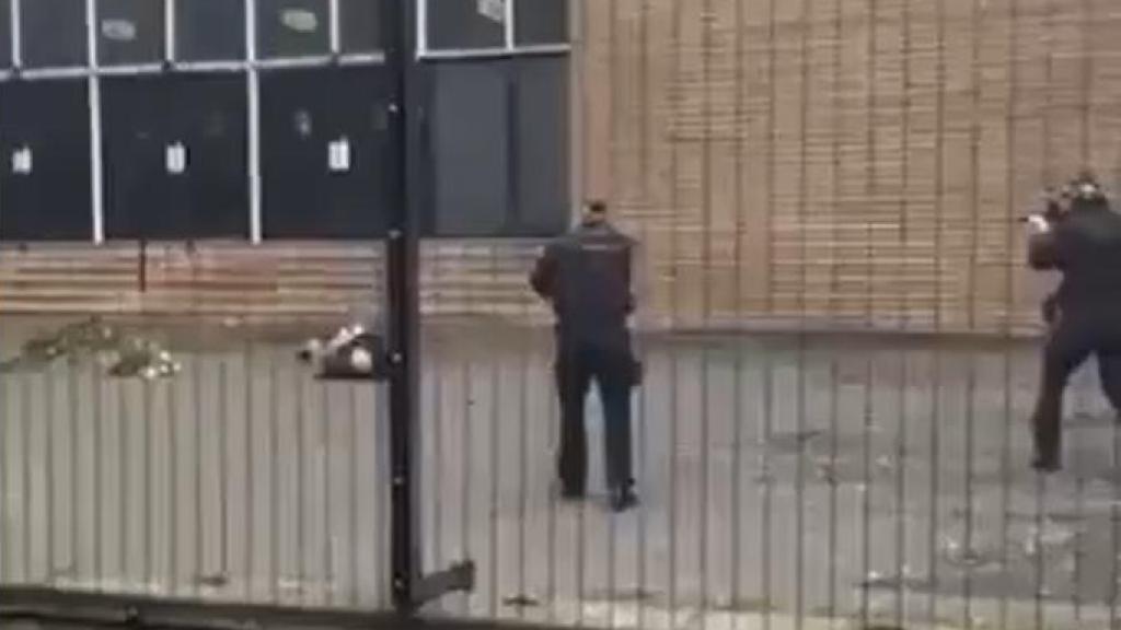 Dos agentes apuntan al sospechoso del ataque, herido en el suelo, antes de disparar.