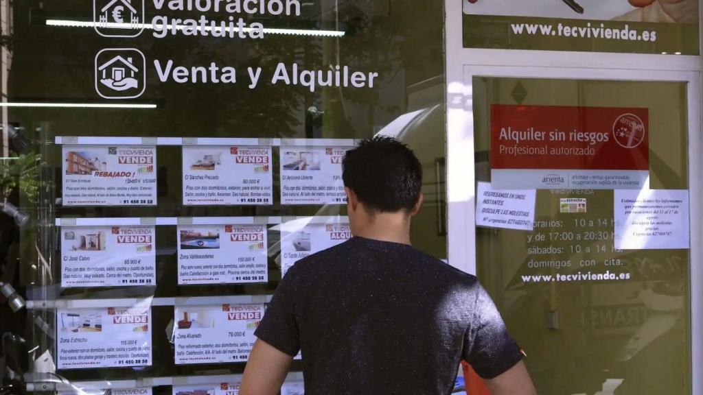 Un hombre observa precios de vivienda de compra y alquiler en una inmobiliaria