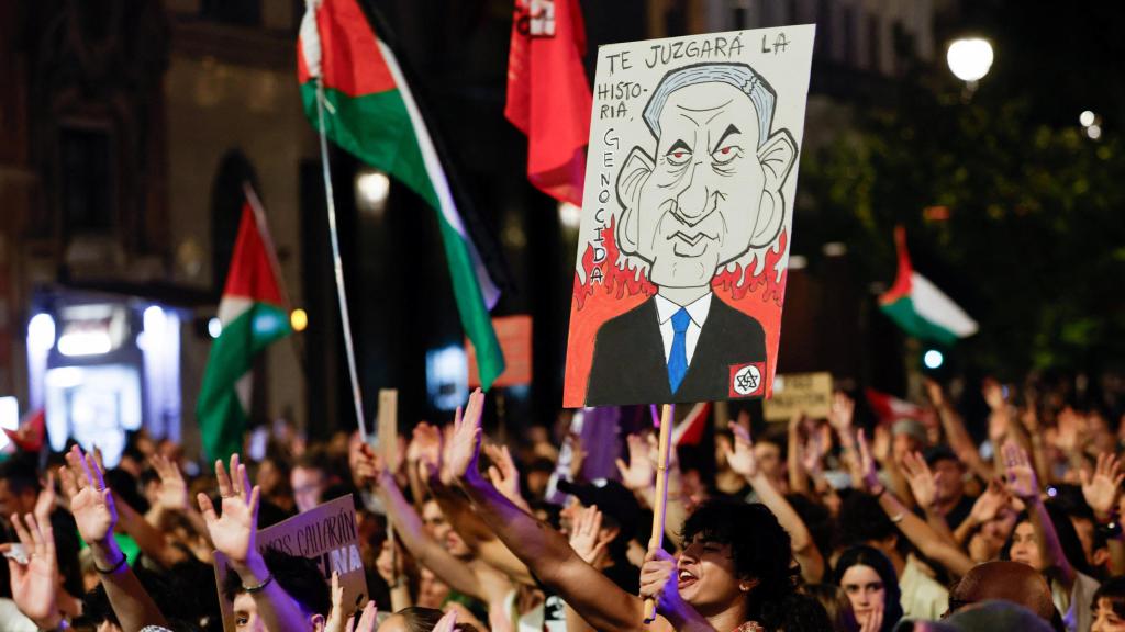 Un grupo de manifestantes sostiene un cartel con una caricatura de Benjamin Netanyahu.