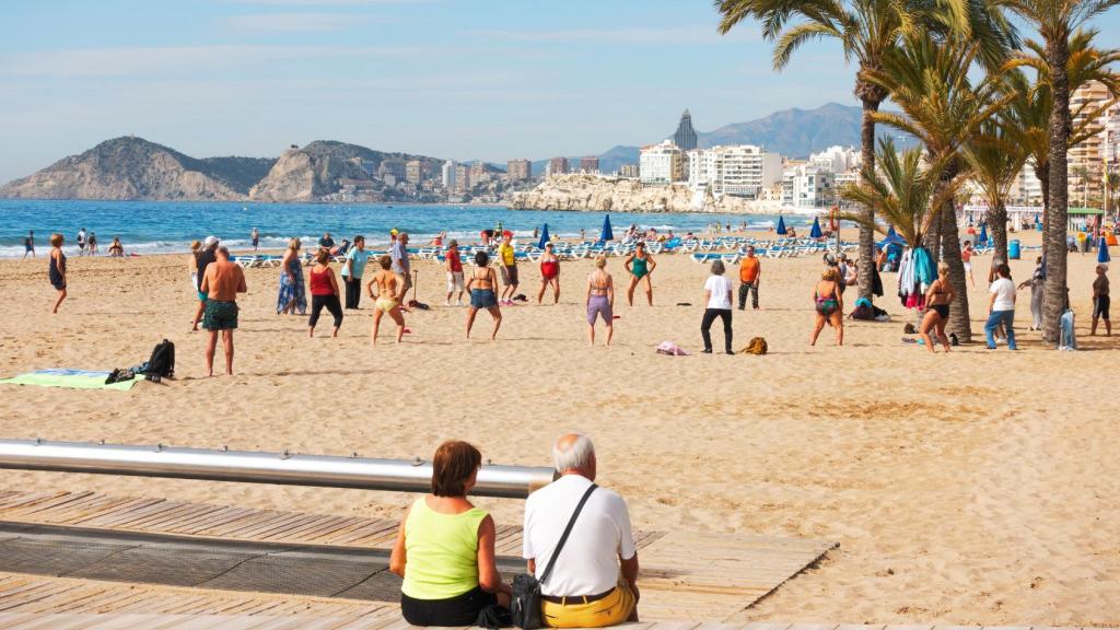 Un grupo de jubilados hace gimnasia en una playa española.