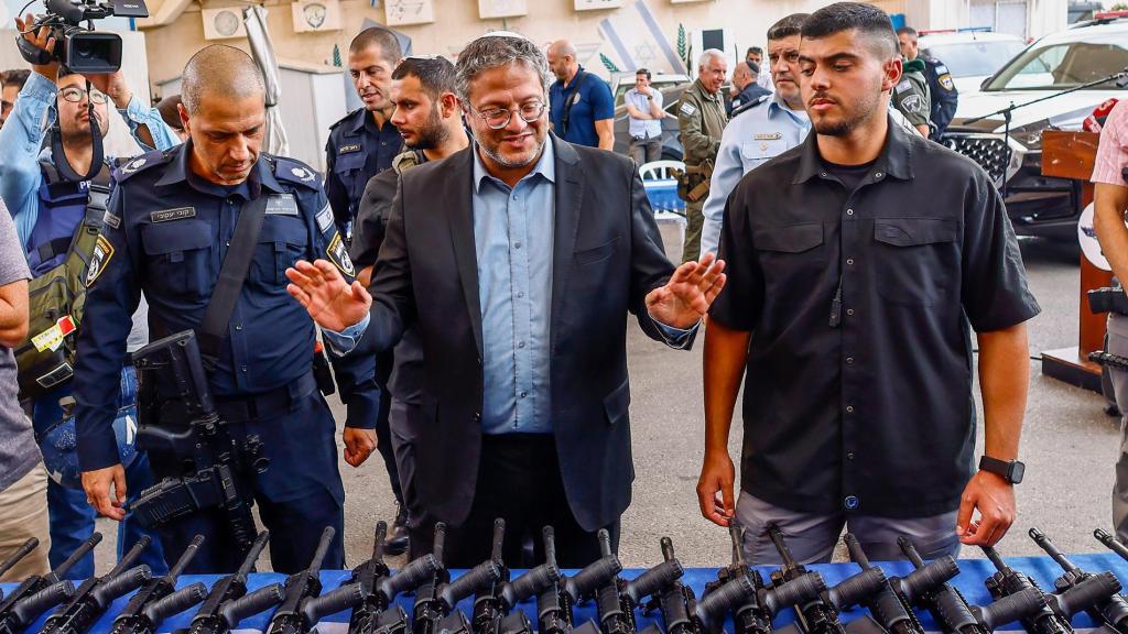El ministro de Seguridad Nacional de Israel, Itamar Ben-Gvir (C), inspecciona fusiles de asalto automáticos M5 que se entregan a voluntarios, miembros de un escuadrón de seguridad.