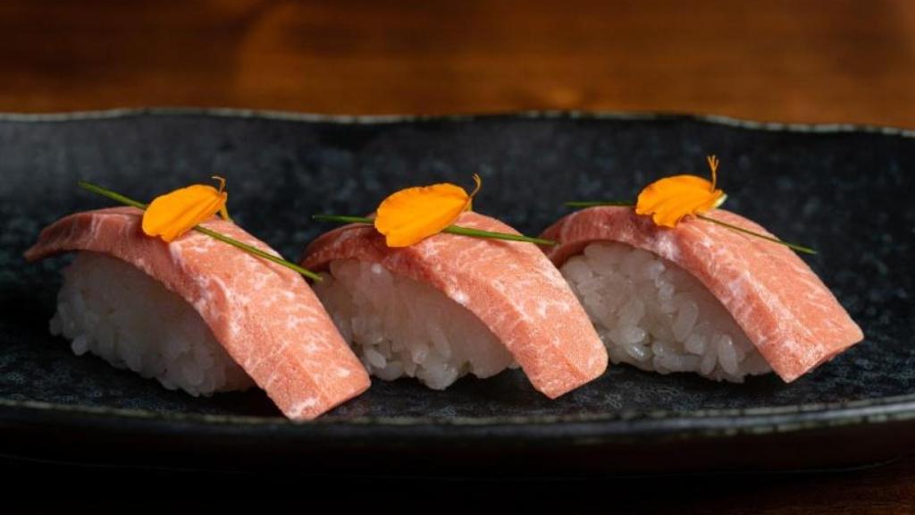Trío de nigiri de atún rojo toro de BlueNalu, cubierto con cebollino en rodajas y pétalos de capuchina