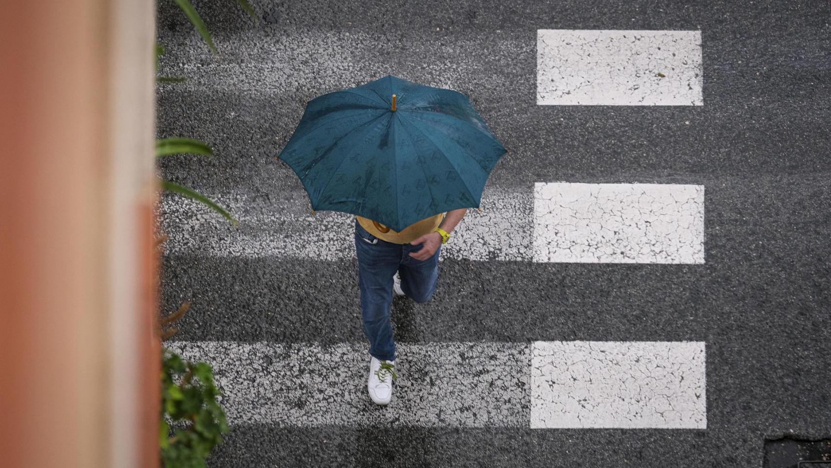 Un hombre se protege de la lluvia en La Foia, en Elche.