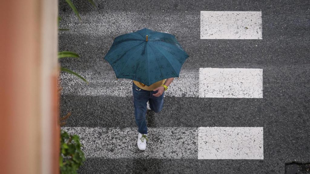 Un hombre se protege de la lluvia en La Foia, en Elche.