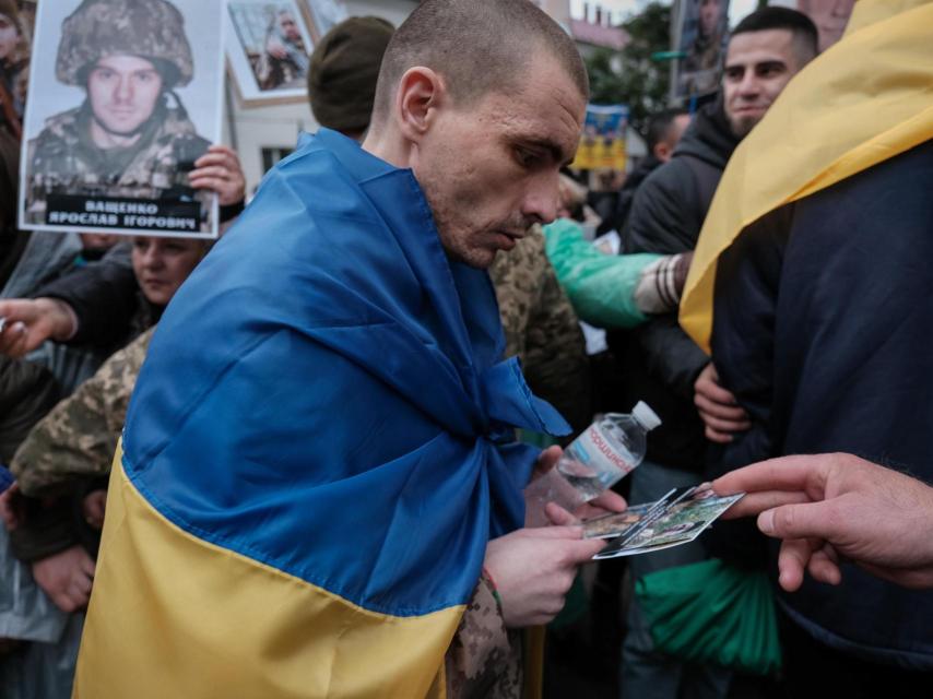 Un prisonero de guerra ucraniano recién liberado recoge los retratos que le entregan las familias de otros soldados cautivos o desaparecidos, que tienen la esperanza de que reconozca a alguien.
