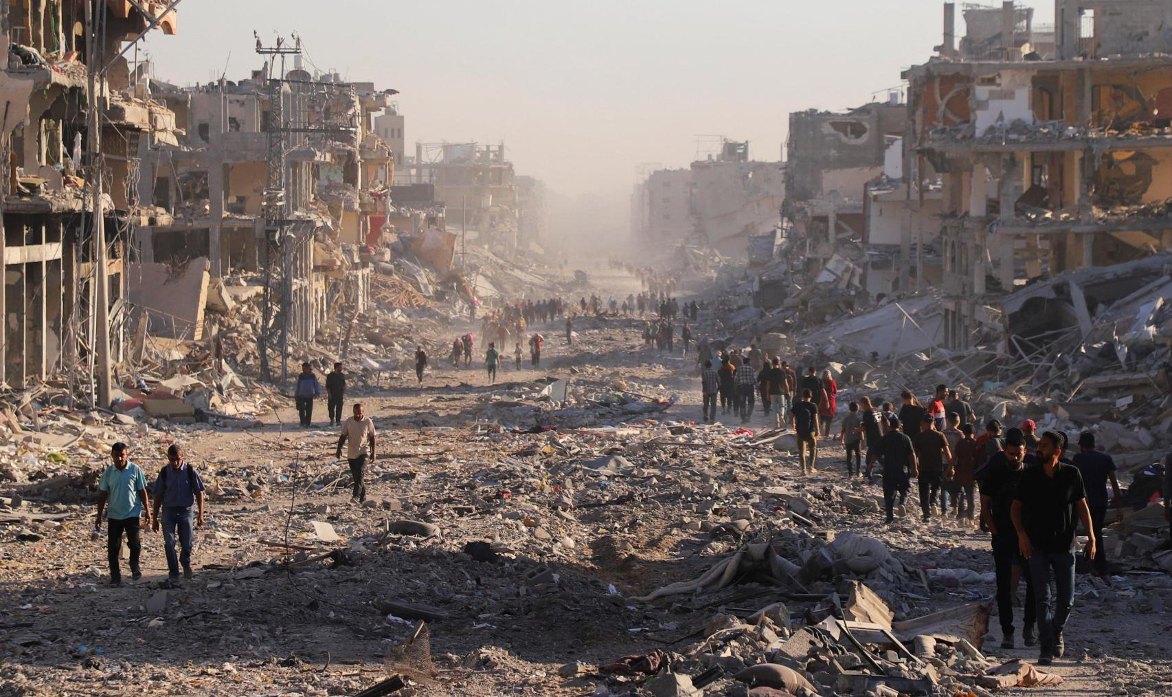 Decenas de palestinos caminan por los escombros de una calle de Ciudad de Gaza.