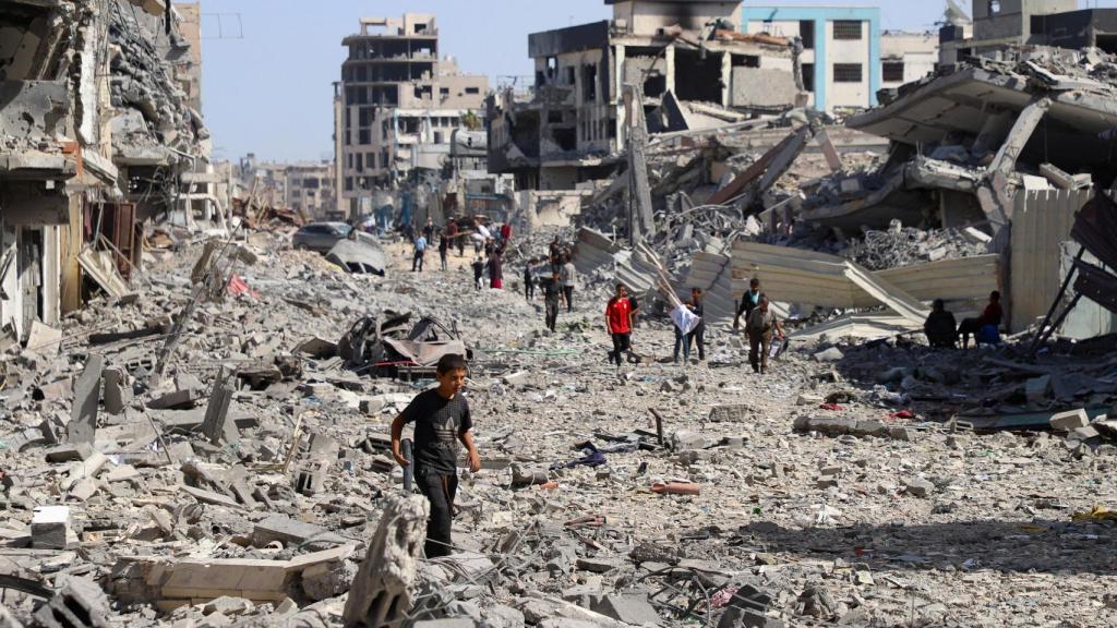 Un grupo de gazatíes tratan de regresar a sus antiguas casas caminando entre los escombros, este sábado.