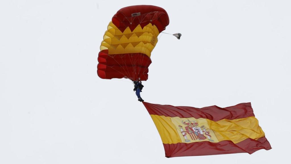 Paracaidista con la bandera nacional a punto de tomar tierra en Madrid
