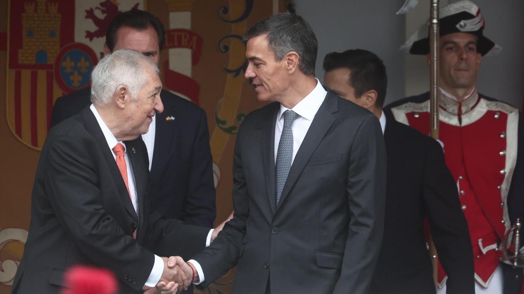 Pedro Sánchez saluda al presidente del Tribunal Constitucional, Cándido Conde Pumpido, en la tribuna de autoridades del desfile de las Fuerzas Armadas.