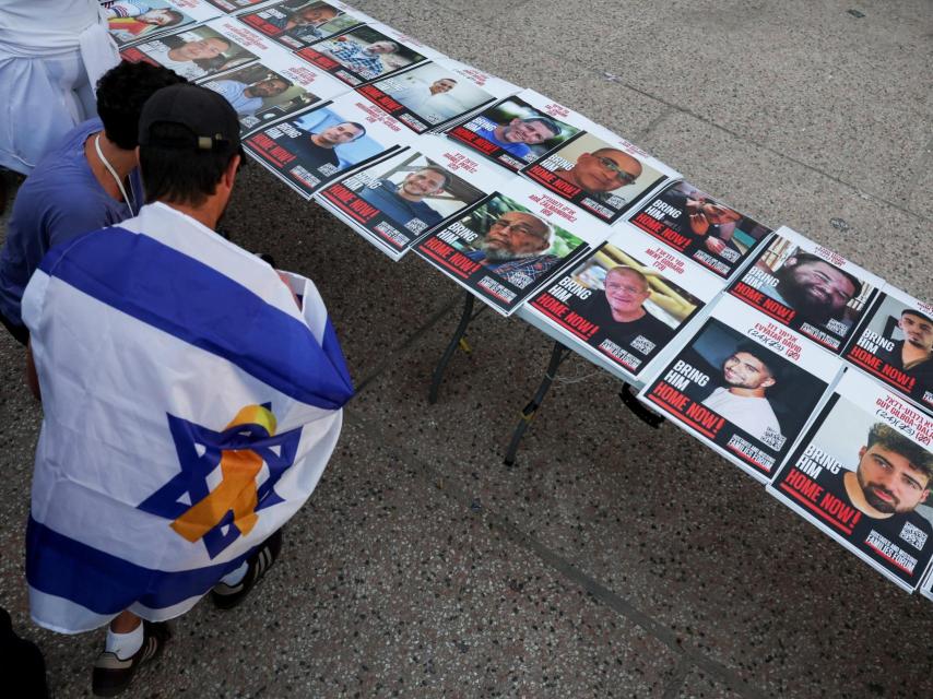 Un hombre contempla las fotografías de los secuestrados en la plaza de los rehenes, en Tel Aviv.