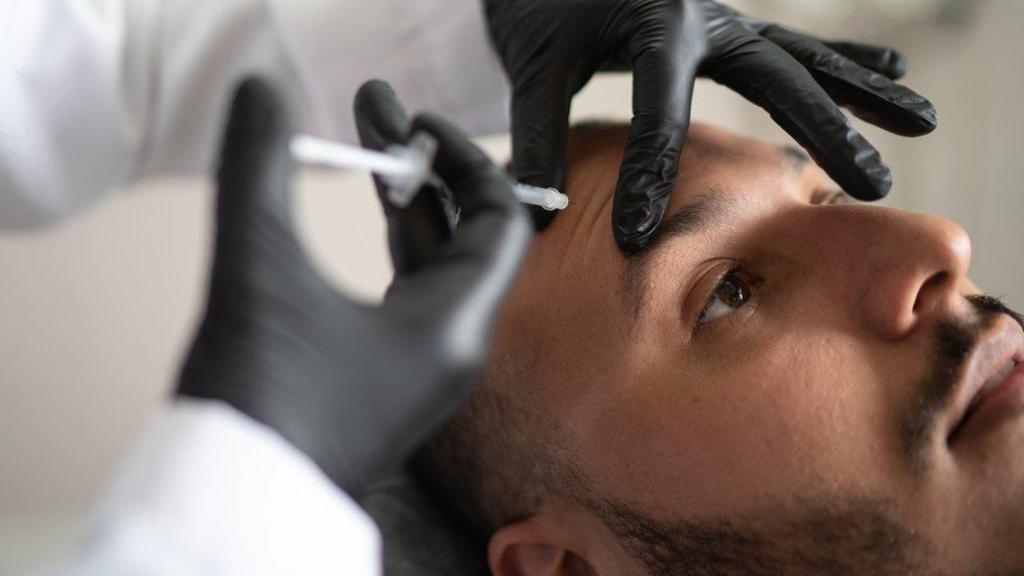 Profesional sanitario administrando ácido hialurónico a un paciente.
