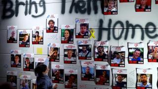 Una mujer coloca una pegatina con la palabra Casa en la foto de un rehén israelí liberado.