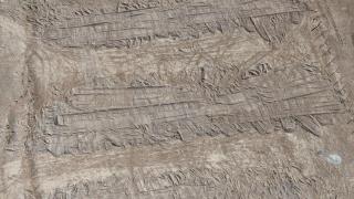 Vista aérea tomada con un dron las huellas dejadas por una excavadora en el suelo que cubre la fosa común en el desierto de Dhumair.